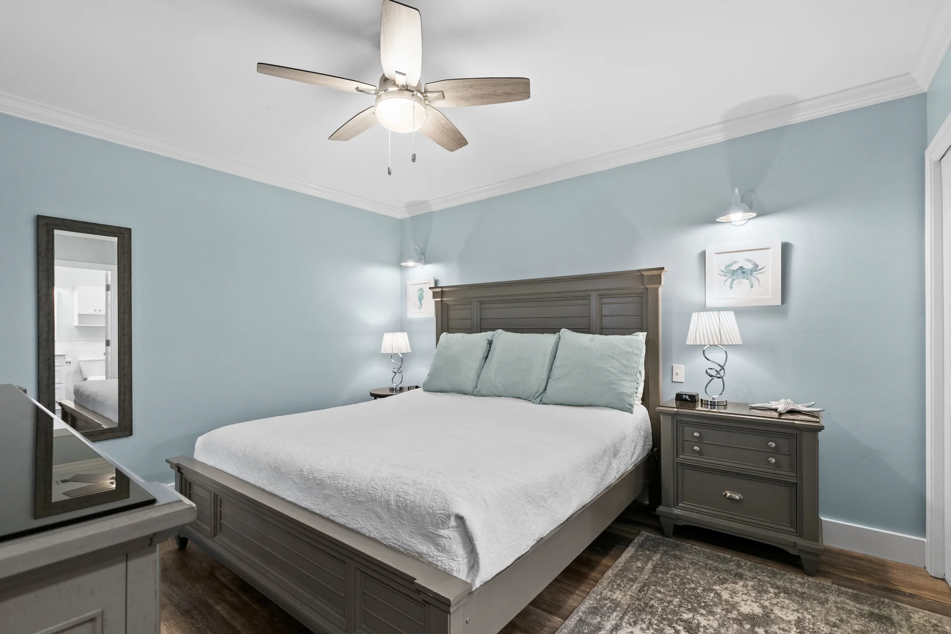 The primary bedroom features a comfortable king-sized bed with head tilt adjustable base, wall sconces, a ceiling fan, large dresser, night stands and wall mounted 48" flat screen tv as well as access to the ensuite bathroom