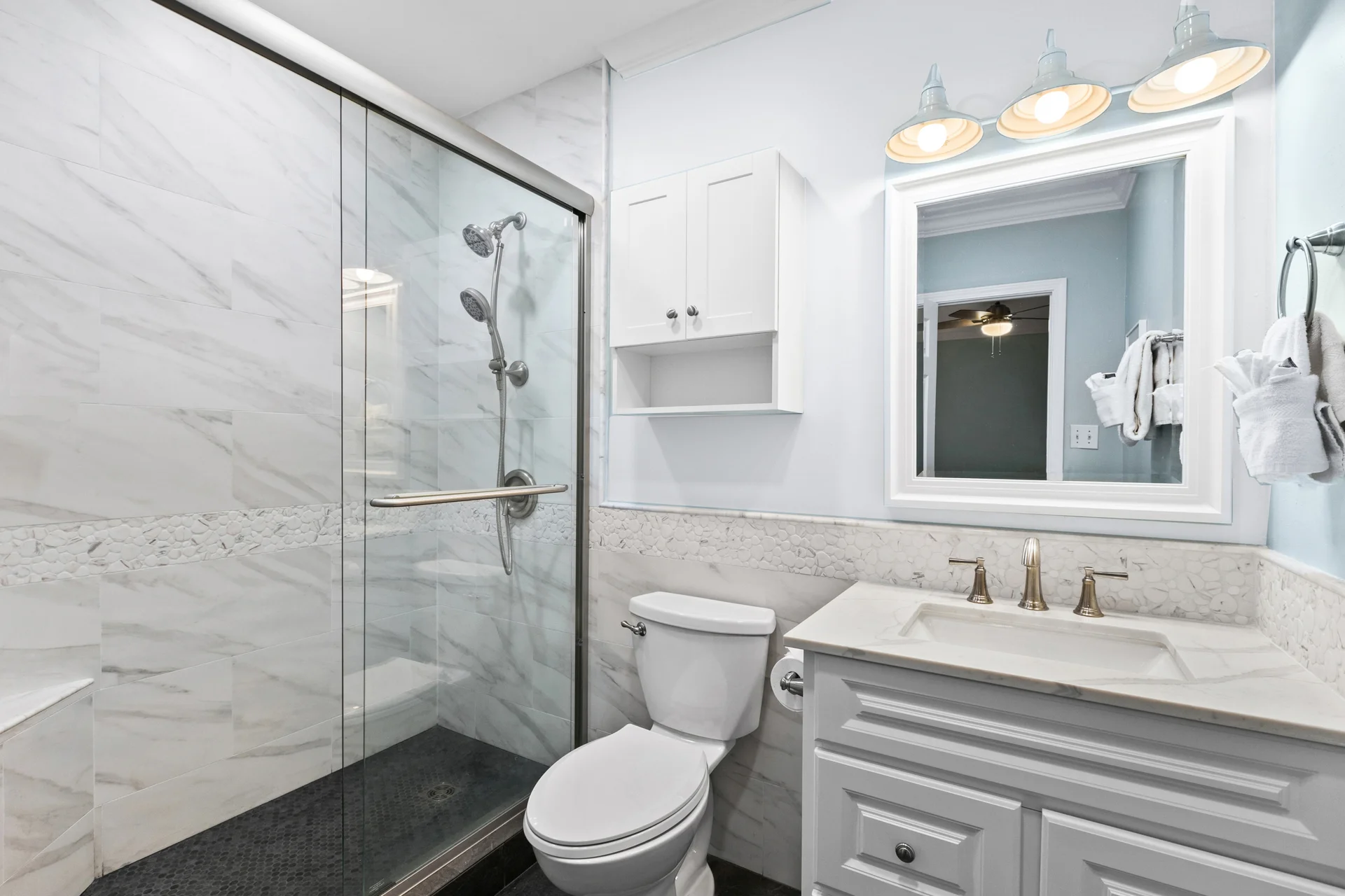 The condo includes two full bathrooms: a primary ensuite bathroom and a hall bath that both feature a spacious glass-enclosed shower, toilet and a vanity with drawers. Additional wall cabinet storage provides convenient space for toiletries and linens, for a clean, modern feel.