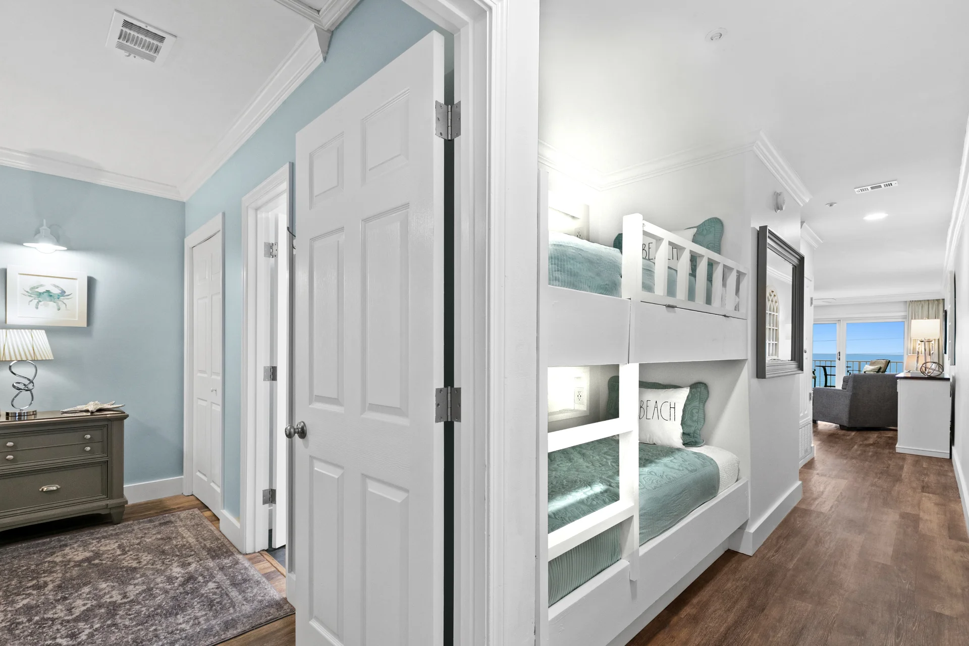 Adjacent to the primary bedroom, cozy hall bunks feature individual reading lights, charging outlets and small personal shelf ledge. A second full bathroom and in-unit washer and dryer laundry closet are located in the cross hall around the corner from the built-in bunks.
